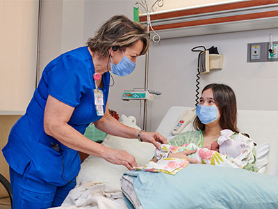 nurse-with-new-mom-and-baby-in-hospital-bed-with-masks